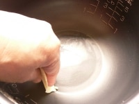 生地用のバターの一部(3～5g)を内釜に塗る。残りのバターは、塊が残っているくらいまで電子レンジで加熱する。バターを混ぜて溶かしておく。<br />
