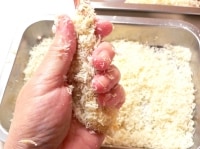尾を右手で持って、左手でえびを優しくにぎって丸く整え、パン粉を安定させる。<br />
