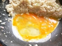 炒飯を向こう側に寄せ、手前に溶き卵を流し入れ、ヘラで大きく混ぜ、半熟の煎り卵を作る。<br />