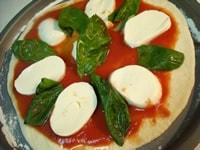 広げたピザ生地に【1】のトマトソースを多めに敷き、スライスしたモッツァレラチーズ、バジルをのせ、最後にオリーブオイルを全体に回しかける。