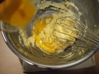 ときほぐした卵を2回に分けて加え、そのつど泡立て器でなめらかな状態になるまでよく混ぜます。<br />