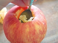 りんごをよく洗い、芯の周りに果物ナイフでグルリと切れ目を入れ、スプーンで芯と種をほじくり出します。このとき、底に穴を開けないように気をつけます。<br />