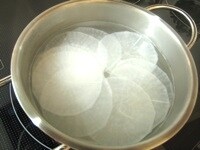 餃子の皮として扱いやすくするため、透明になるまで大根をゆでる。冷水で冷やした後、キッチンペーパーで水気を拭き取る。<br />