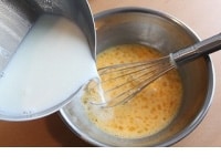 ボウルに卵（全卵と卵黄）を入れ、泡立て器で卵を溶きほぐします。ここで空気が入るとプリンが膨らんでしまうので、空気が入らないように、泡立て器は左右に動かすようにします。泡が立たないように、ゆっくりと牛乳を卵に注いで、泡立て器で混ぜます。