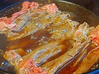 すき焼き鍋を火にかけ、牛脂（なければサラダ油を敷く）をなじませます。肉を敷いて軽く焼いたら割り下を適量加え、肉に下味をつけます。<br />