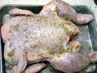 【1】のハーブ塩を、お腹部分を上にした丸鶏にすり込むように塗る。その際、脇などにも丁寧にすり込む。すり込んだら、冷蔵庫で1～2時間ねかす。<br />