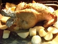 鶏肉から脂が出てきたら、温度を180℃に下げ、【6】のジャガイモを入れ、40分～1時間程度焼く。途中30分位で、ジャガイモの焦げ目をひっくりかえすようにする。鶏に金串を刺して、血が出なければ焼き上がりで、皿に盛る。<br />