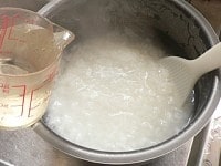 スイッチが切れたら内釜ごと取り出す。おかゆをヘラで混ぜ、冷水を2カップ強(450ccぐらい)混ぜて温度を下げる。<br />