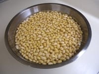 大豆はきれいに洗い、3倍ほどの水に一晩浸けておきます。大豆は2倍ほどに膨らむので大きめのボウルなどに入れます。<br />