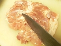 モモ肉をまな板の上に広げ、スジを切り、分厚い部分を切り開いて、厚さをそろえる。<br />
