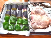 オーブンの角皿の半分にクッキングシートを引き、野菜を並べます。もう半分にはアルミホイルを引き、鶏肉の皮を上にし、塩をふります。<br />