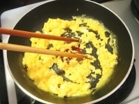 フライパンにサラダ油を熱し、味付けした卵液を流し込み、卵に8割程度火が通ったところで火を止めます。余熱で火を通しながら、菜箸で卵の面にグルグルと円を描き、卵をポロポロにします。<br />