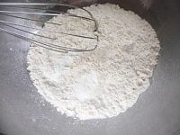 薄力粉とベーキングパウダーを泡だて器でグルグル混ぜる。次に砂糖と塩を混ぜる。<br />