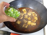 再び煮立ったらねぎを加え、豆腐をさっくりと返しながら１分ほど煮ます。<br />