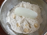 粉類にグラニュー糖とバターを加え、バターが細かい粒状になるよう、カードでざくざくと切り混ぜます。<br />