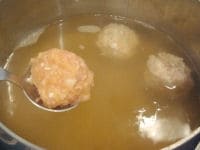 鍋にかつおだしを入れて火にかけます。沸騰したら、スプーンで鶏団子の種をすくって形を整え、鍋の中に入れていきます。<br />
