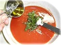 トマトソースを作ります。ボウルの上にザルをのせ、ホールトマトをへらで裏ごしします。そこに千切りしたバジルの葉、塩、エクストラヴァージンオリーブ油を加え混ぜ合わせます。さわやかな風味のトマトソースです。<br />