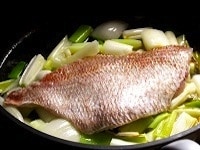真鯛は皮目に塩をふる。ネギがしんなりしたら、真鯛を上に載せ、日本酒を入れてフタをする。沸騰したら弱火にし、5～7分ほど、鯛にギリギリ火が通る程度に蒸す。