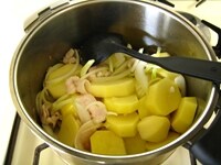 鍋に油を入れ、中火にかけます。豚肉、じゃがいも、玉ねぎを加え、油がまわるよう炒めます。<br />