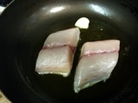 フライパンにオリーブオイルとにんにくを入れ中火にかける。にんにくの香りがたったら、白身魚を皮目から入れる。<br />