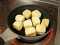フライパンにごま油を入れ熱します。豆腐を入れ、弱火で全面がきつね色になるまでゆっくりと焼きます。焼き上がったらキッチンペーパーに取り出し、余分な油をきります。<br />