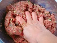 ひき肉と切った野菜、パン粉、調味料をボールの中に入れ、よくこねて混ぜ合わせます。粘り気が出るまでこねたら、20等分にします。<br />