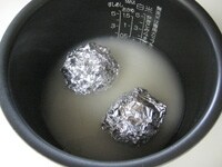 米を研ぎ、炊飯に適した量の水（分量外）をいれます。<br />
洗ったじゃがいも、卵をアルミホイルで包み、米の上にのせ、炊飯をします。<br />