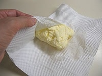 でき上がったバターをキッチンペーパーに包みます。2～3回取り替えて、バターの余分な水分を取り除きます。<br />