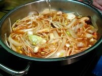 鍋にごま油を入れ、強火にかけます。長ねぎ、生しいたけ、もやし、半量の白菜キムチを入れて炒めます。次に合わせ調味料を加えたスープを加え、強火で煮立たせます。（ 豚バラ肉を使うときは野菜と一緒に炒めます）