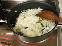 次に無洗米を入れて、米が半透明になるまで炒めます。米にバターがなじんだら、シャンパン半量（180cc）を入れ強火で木べらで混ぜながら、アルコール分を飛ばします。