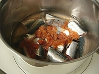 鍋に角切りした昆布を敷き、その上にいわしを重ならないように並べます。水200ｍｌと酒を加え中火にかけます。煮立ったらアクを取り除きます。<br />
<br />