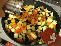 なすとズッキーニも加え、塩少々をふりかけて炒めます。炒める野菜類は８割ほど火が通った状態になっています。