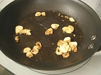 フライパンにオリーブオイルと薄切りしたにんにくを入れ中火にかけます。にんにくがきつね色になったら取り出します。これはガーリックライスに使います。<br />
