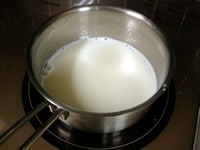 鍋に牛乳を入れ中火にかけます。沸騰寸前に火を止め残りのグラニュー糖（30g）を加え溶かします。<br />