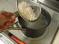 米は洗いざるにあげ、水気を切ります。鍋に水とスープの素を入れ中火にかけます。沸騰したら水気を切った米を加えます。<br />
