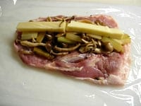 鶏もも肉は、包みやすいように、肉の厚みを包丁で調整し平らにします。鶏肉の両面に軽く塩、コショウを振りかけ、炒めたしめじとセロリ、チーズをのせます。ラップや巻きすを使って巻きます。中の具を入れ過ぎると巻きづらくなります。<br />