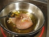 鶏胸肉に塩コショウを振りかけます。フライパンにサラダオイルと潰したニンニクを入れ中弱火にかけます。鶏肉は皮目を下にして焼き油をスプーンですくって肉にかけながらゆっくりと焼き上げます。<br />