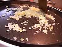 200度に温めたホットプレートにオリーブオイル大さじ1を入れ、にんにく、たまねぎ、しょうがのみじん切りをよく炒めます。