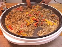 米をつまんでみて少し芯が残る程度に炊き上げたら、イカ墨と袋から絞ったイカのワタを加え、全体を混ぜ合わせます。