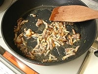 ベーコンは細切りします。フライパンを熱し、ごま油とみじん切りのにんにくを入れます。香りが立ったらベーコンを加え、カリッと炒めます。