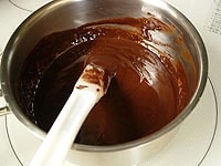 チョコレートが溶けて混ざったら、バターをゆっくりと加え混ぜ合わせます。最後にリキュールを加え、そのまま少し冷まします。<br />