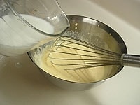 ボウルに卵黄を入れハンドミキサーで泡立て、グラニュー糖を2回に分けて加えます。生地が白っぽくリボン状になるまで泡立てます。2番の半量を少しずつ加えながら混ぜ合わせます。