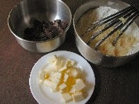 板チョコは適当な大きさに割ります。バターはさいの目切りにします。粉類と砂糖、塩は1つのボールにまとめて入れ、泡立て器でよく混ぜ合わせておきます。オーブンは180度に設定し、あらかじめ温めておきます。<br />