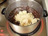 アクとりが終わったあずきを鍋に戻し3～4cmくらいかぶる水で蓋をして煮ます。煮立ったら弱火で柔らかくなるまで煮ます。水は1cmくらいかぶっている状態です。もし煮詰まったら水を差します。あずきが柔らかく煮えたら三温糖を加えます。<br />
<br clear="all" />
