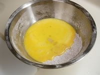 合わせて振るった粉に溶きほぐした卵を加え、へらで混ぜ合わせます。<br />